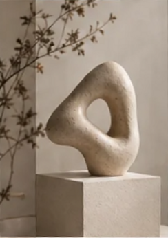 Hand-carved cream loop sculpture on a stone pedestal
